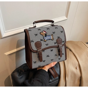 Detail of vintage houndstooth handbag with dachshund embroidery and stylish bow accents