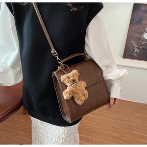 Dettaglio dello zaino vintage in pelle sintetica marrone con goffratura e ciondolo a orsetto