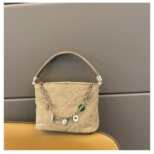 Detail of beige suede bucket bag with quilted patterns and decorative gold metal chain