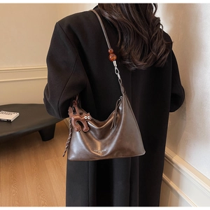 Detail of dark brown crescent shoulder bag with amber beads and a leather cat charm