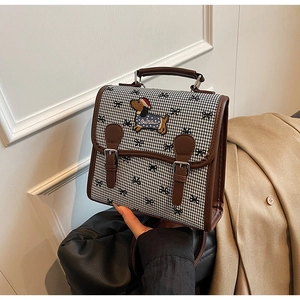 Detail of houndstooth fabric with puppy embroidery and leather handles on bag