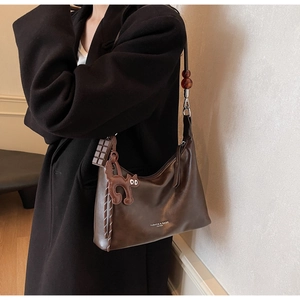 Detail of dark brown leather hobo bag with creative chocolate and cat charms