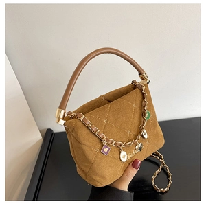 Detail of brown quilted suede handbag featuring star embroidery and gold charm chain strap