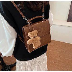Dettaglio dello zaino vintage in pelle marrone con ciondolo a orso e logo a rilievo