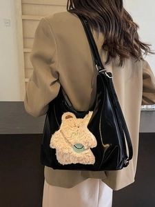Sac à bandoulière noir brillant avec broderie ours en peluche blanc sur un mannequin