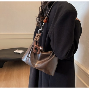 Close-up of a brown leather shoulder bag featuring unique resin beads and cat charm