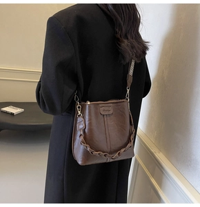 Detail of retro bucket bag showing dark brown PU texture and wide printed shoulder strap