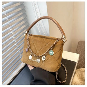Detailed shot of brown quilted suede handbag with decorative metallic charms and chain strap