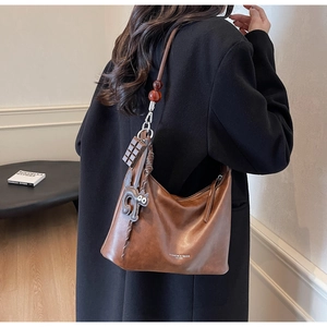 Detailed back view of a retro brown leather hobo bag with unique cartoon cat charms