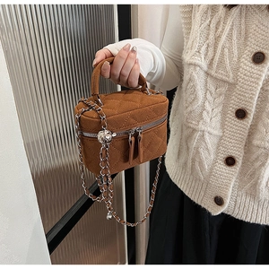 Close-up of brown quilted suede bucket bag featuring silver chain and metal adjuster