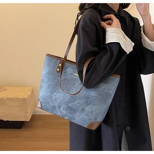 Detail view of large blue marble tote bag with brown leather handles and gold studs