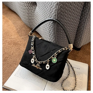 Detail of black quilted velvet bucket bag with gold logo and heart charm chain strap