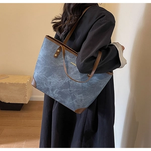 Rear view of a model wearing the large vintage tote bag with blue patterns and brown trim