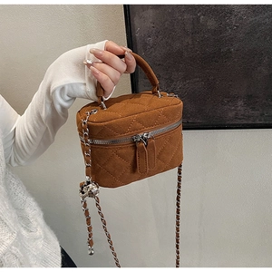Detail of brown quilted mini box bag with silver chain strap and hollow metal ball