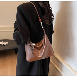 Brown leather hobo bag featuring amber beads and a removable cat pendant detail