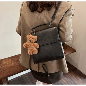 Dettaglio della borsa a tracolla vintage in pelle nera opaca con ciondolo a forma di orsetto