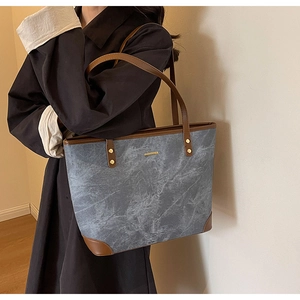 Detailed shot of large grey marble tote bag with brown leather trim and gold metal accents