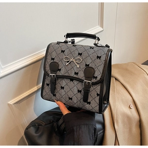 Close-up of retro plaid handbag featuring black bow patterns and silver metal buckle