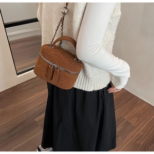 Close-up of brown quilted suede mini bucket bag with chain strap and silver ball slider