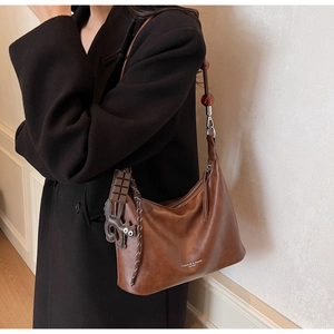 Detail of vintage brown leather hobo bag with cat charm and red bead strap accents