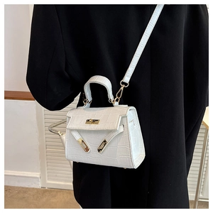 Close-up of white crocodile pattern handbag featuring a classic gold twist lock and strap