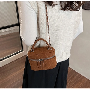 Detail of vintage brown quilted mini chain bag worn by model in a cozy indoor setting