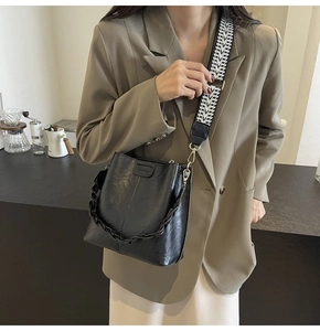 Detail of black leather bucket bag featuring a stylish black and white geometric wide strap