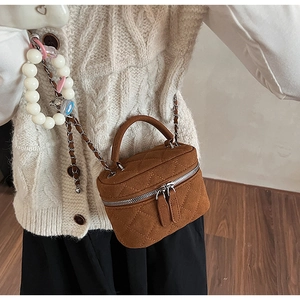 Close-up of caramel quilted suede crossbody bag styled with a white knit sweater