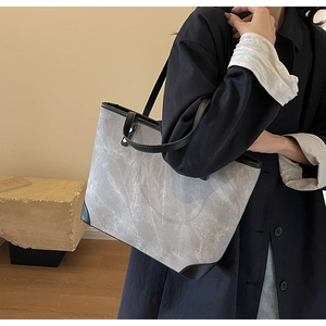 Detail of stone-patterned tote bag showing gray textured fabric and black leather trim