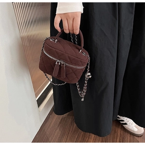 Detailed view of brown quilted crossbody bag with silver chain and dual zipper design