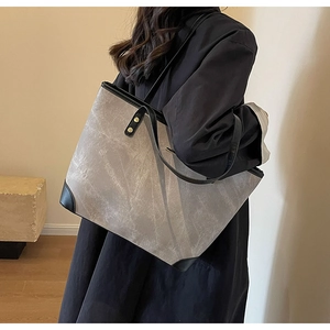 Close-up of grey oversized tote bag featuring black reinforced corners and matte texture