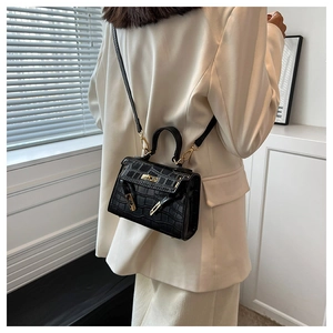 Close-up of elegant black crocodile pattern handbag with gold hardware on a model
