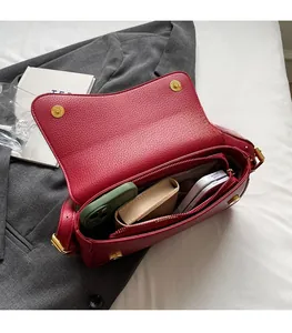 Detail view of red litchi texture handbag showing spacious interior and golden magnetic buckle