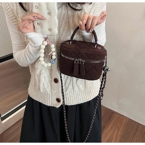 Detailed view of the dark brown quilted mini bucket bag with chain strap on a model