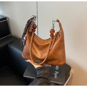 Detail of vintage caramel brown leather bag with amber beads and tassel charm decoration