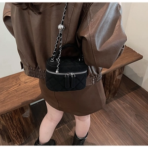 Detail of black quilted velvet box bag with silver heart charm and metal chain strap