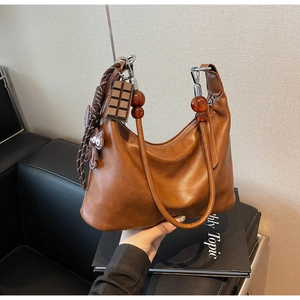 Close-up of brown leather hobo bag with chocolate charm and amber bead detail