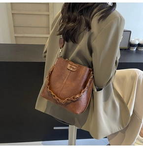 Detail of vintage brown bucket bag featuring woven leather trim and gold metal hardware hooks
