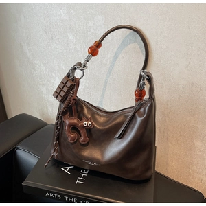 Detail of dark brown leather crescent bag featuring amber beads and chocolate charm