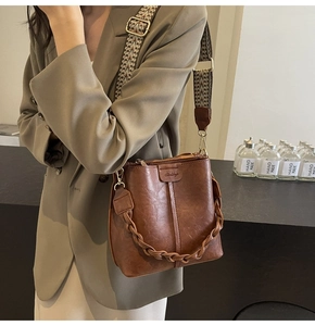 Brown retro PU leather bucket bag with wide jacquard strap shown on a model