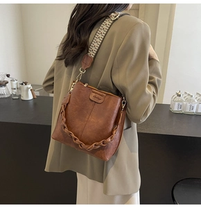 Brown vintage bucket bag with woven handle and jacquard strap shown on model