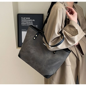 Detail of grey-brown tote bag with black leather base reinforcement and metal rivets