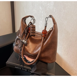 Detailed shot of brown vintage handbag featuring chocolate charm and amber bead strap