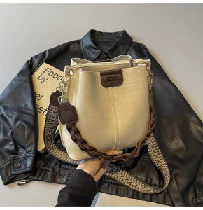 Detail of cream leather bucket bag with bohemian geometric woven shoulder strap