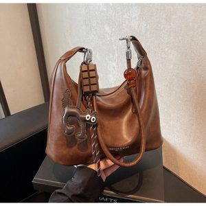 Close-up of brown PU leather handbag with chocolate charm and cat pendant accessory