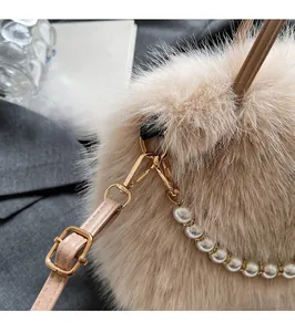Gros plan d'un sac à main beige en peluche avec boucles dorées et chaîne de perles chic