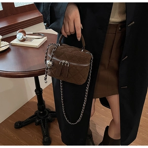 Detail of coffee brown quilted crossbody bag with heart charm and silver chain strap