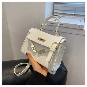 Detail of white crocodile texture on elegant handbag with golden clasp and leather strap