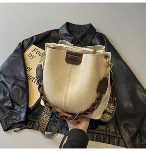 Detail of cream bucket bag showing woven handle and geometric wide fabric strap