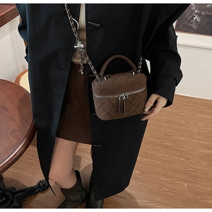 Detailed macro view of brown quilted suede bucket bag with gold crush ball chain